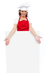 Image showing Female chef posing behind blank white billboard