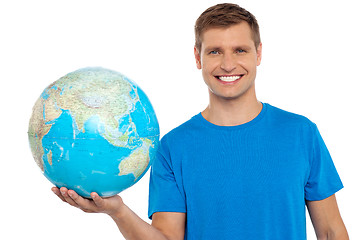 Image showing Young cheerful man holding a globe in his hand