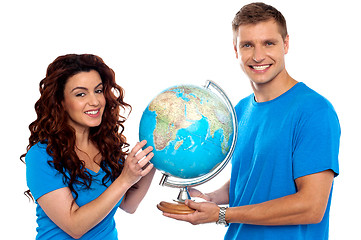 Image showing Joyful couple holding globe and smiling at camera