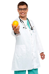 Image showing Happy young doctor offering you orange