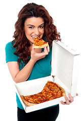 Image showing Young cheerful girl enjoying pizza alone