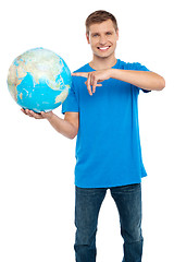 Image showing Smart guy pointing at the globe. Dressed in casuals