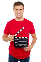 Image showing Smiling young guy holding clapperboard