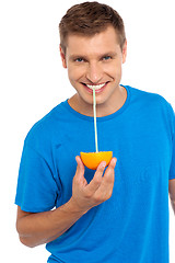 Image showing Cool guy sipping juice from half orange