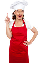 Image showing Beautiful smiling female chef indicating upwards