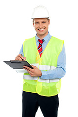 Image showing Smiling young construction engineer writing