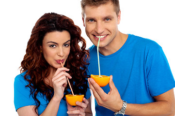 Image showing Closeup of couple cuddling and sipping orange juice