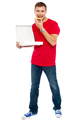 Image showing Causal  smart guy holding pizza box and eating a piece