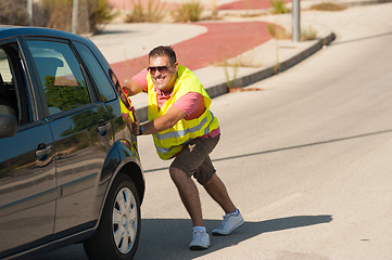 Image showing Pushing his car