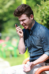 Image showing Young man angry on telephone in the park