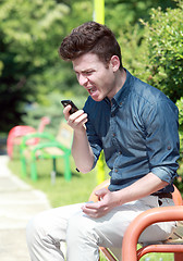 Image showing Young man shouting on telephone in the park