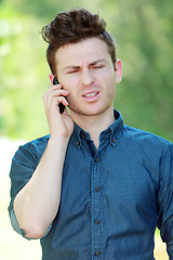 Image showing Disappointed young man at telephone