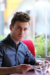 Image showing Young handsome man in restaurant looking at menu