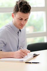 Image showing Young adult man writing note