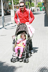 Image showing Happy father smiling with his daughter in baby carriage