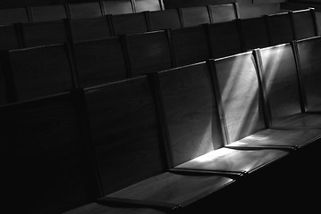 Image showing Black and white image of Rows of church pews with stream of ligh