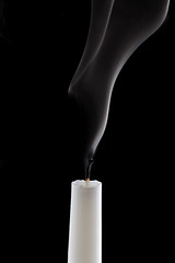 Image showing White candle with smoke on black background.