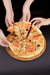 Image showing A group of people taking slices of pizza