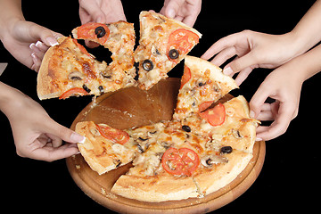 Image showing A group of people taking slices of pizza