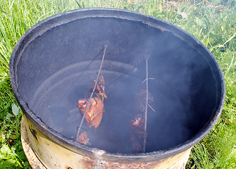 Image showing Ecologic fish smoke in smokehouse rusty barrel 
