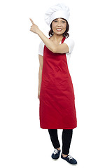 Image showing Beautiful female chef pointing at the copy space