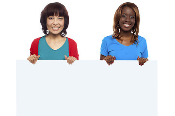 Image showing African and Asian marketing personnel holding billboard