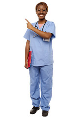 Image showing Female doctor pointing at copy space, holding clipboard