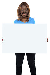 Image showing Smiling african female model holding billboard