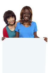 Image showing Young ethnic friends behind blank ad board