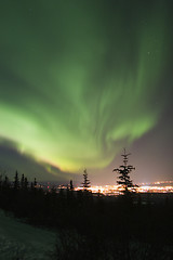 Image showing Active Aurora Borealis in the sky over town lights