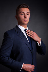 Image showing young businessman adjusting his tie 