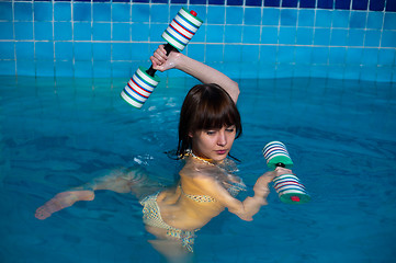 Image showing Attractive girl trains in aqua aerobics