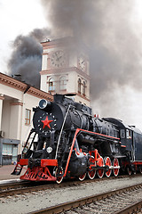 Image showing Old steam train is leaving a station