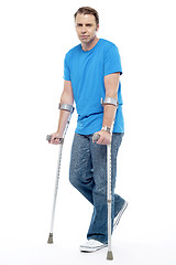 Image showing Painful expression by young man walking with help of crutches