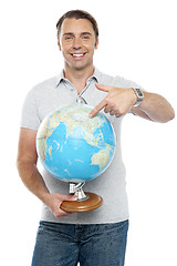 Image showing Isolated young man pointing at globe