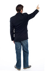 Image showing Back pose casual guy pointing at the copy space area