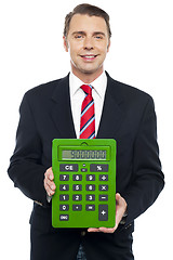 Image showing Young businessman showing big green calculator