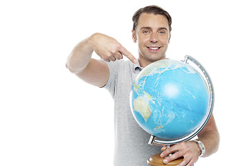 Image showing Man holding globe and pointing over it