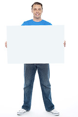 Image showing Handsome casual guy holding blank ad board