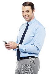 Image showing Smiling young manger sending sms from phone