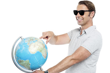 Image showing Handsome guy in goggles pointing at globe