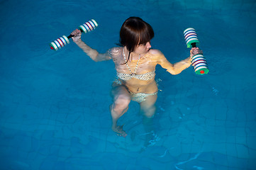 Image showing Attractive girl trains in aqua aerobics