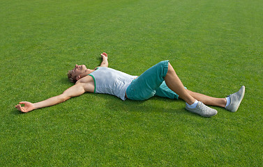 Image showing Sporty guy relaxing on green training field