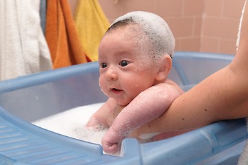 Image showing Cute baby in a bathtub with foam cap on his head