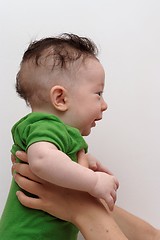 Image showing Cute smiling baby held by his mother profile view