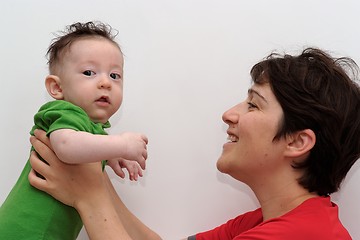 Image showing Cute baby held by his smiling mother looks toward the camera