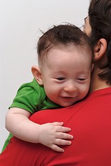 Image showing Rear view of cute smiling baby boy  looking over mother  shoulder