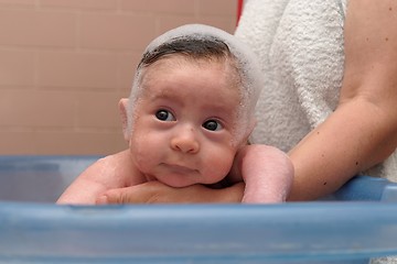 Image showing Cute baby in a bathtub with foam cap on his head