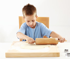 Image showing Small boy rolling dough for cookies 