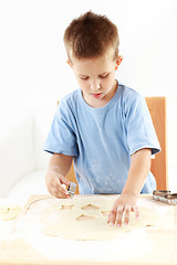 Image showing Small boy cutting cookies